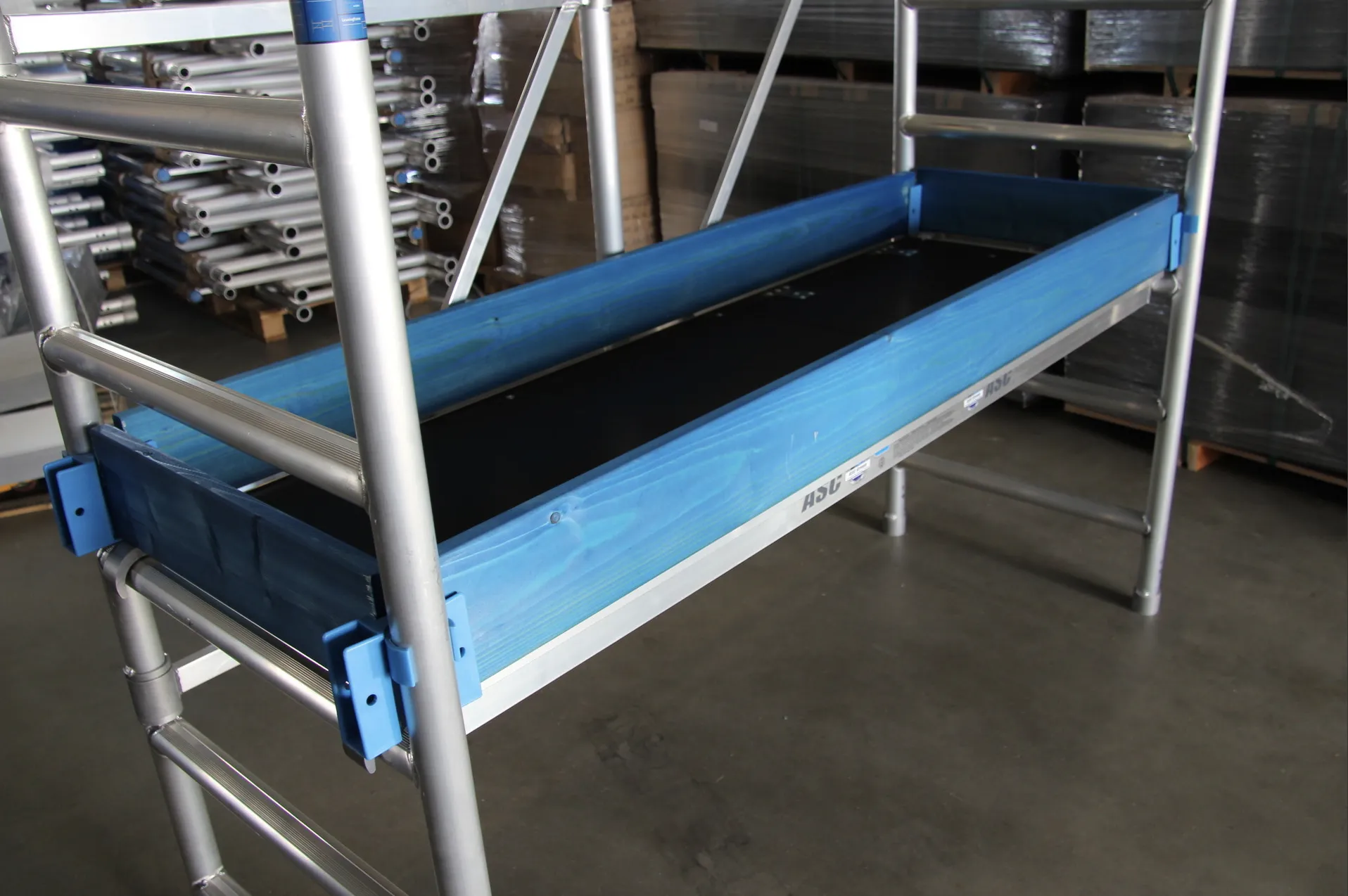 Struttura di ponteggio con supporti blu e piano di lavoro in legno.
